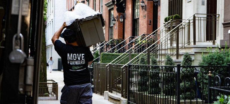 A professional mover from Movers Not Shakers! carrying a reusable moving box