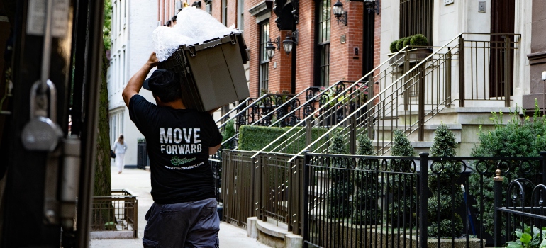 A professional mover carrying a reusable moving container on his shoulder