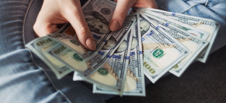 A person holding a fan made of dollar bills