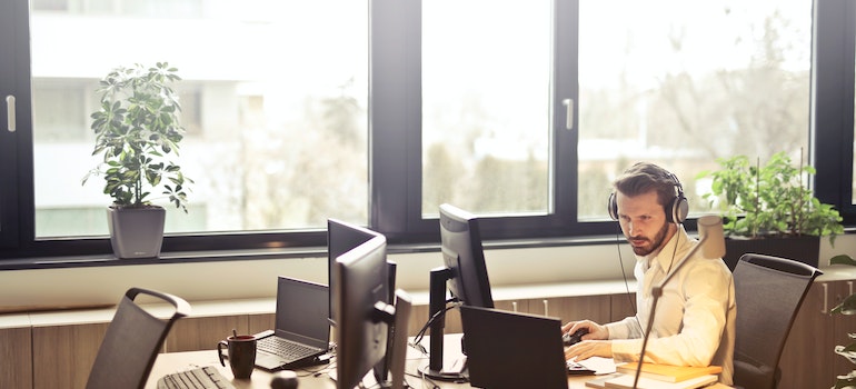 A man wearing headphones while working in an office alone