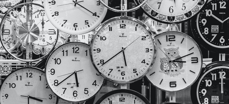 A black and white photo of many clocks