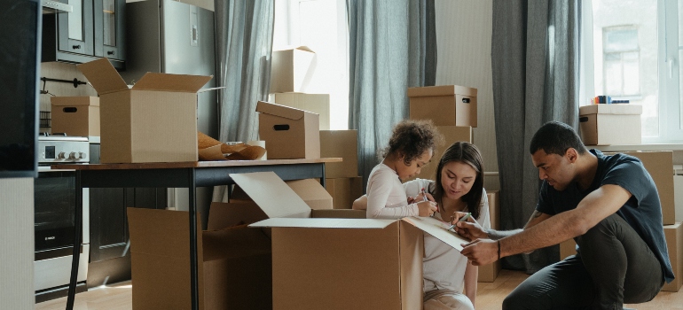 A family making a moving plan together and drawing on a cardboard box