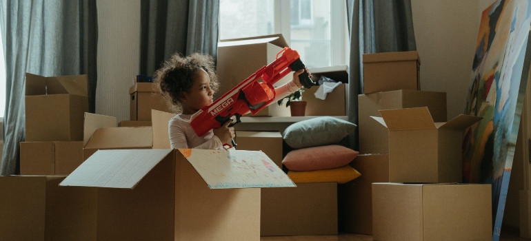 A girl paying with a toy gun in a moving box