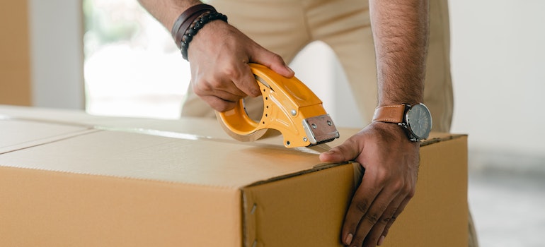 A man sealing a moving box with tape
