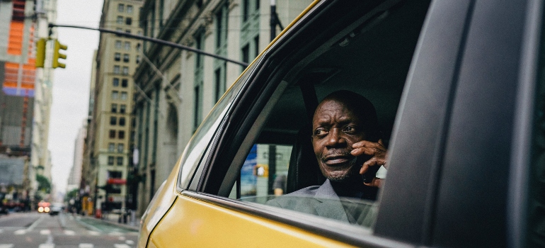 A man talking on the phone while riding in a taxi, representing moving from Manhattan to the Bronx