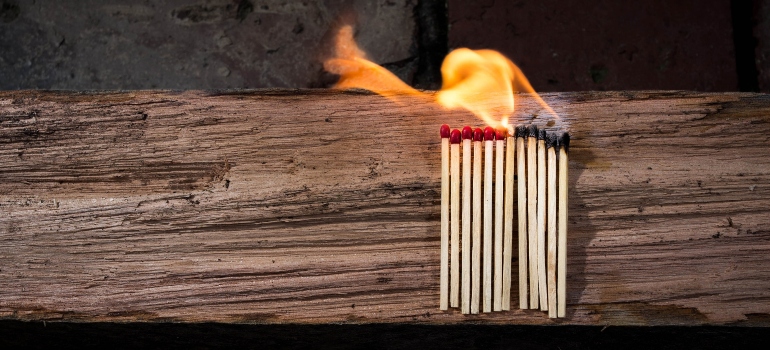 Several matches burning on a wooden surface representing questions to ask your movers