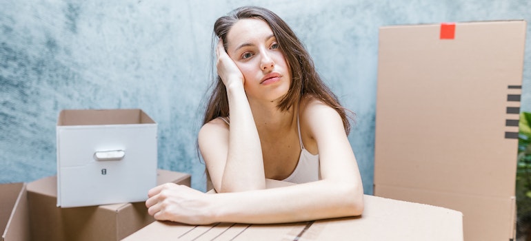 A bored young woman resting her head on her hand and leaning on a stack of moving boxes