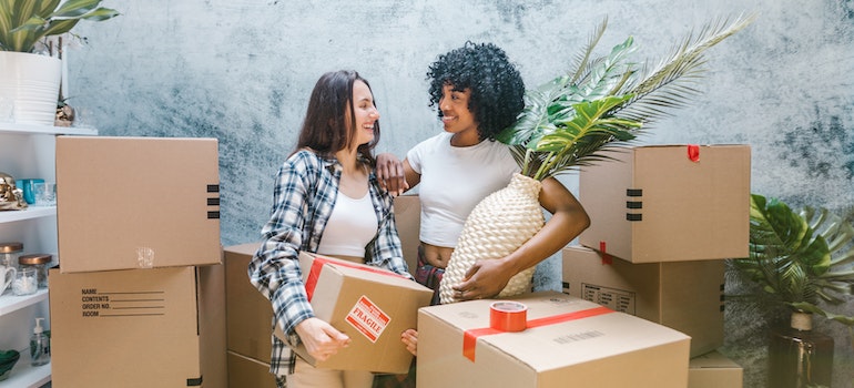 Two women smiling and talking among moving boxes