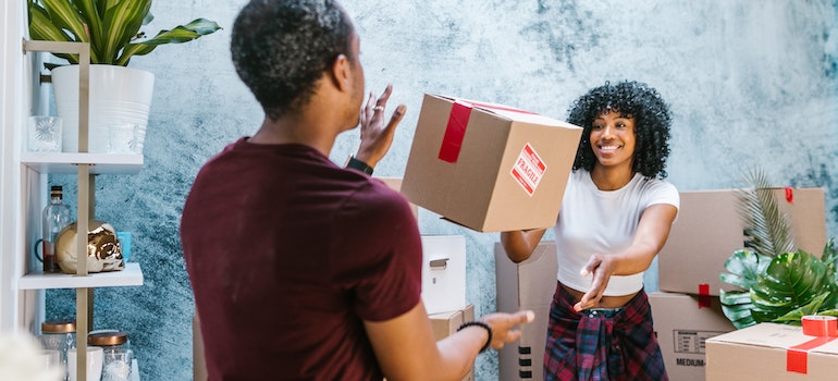 A woman throwing a cardboard box to a man