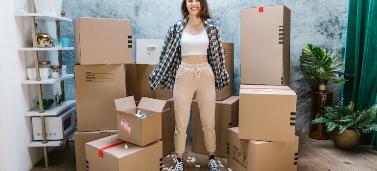 A woman standing among cardboard boxes while moving a studio apartment in NYC