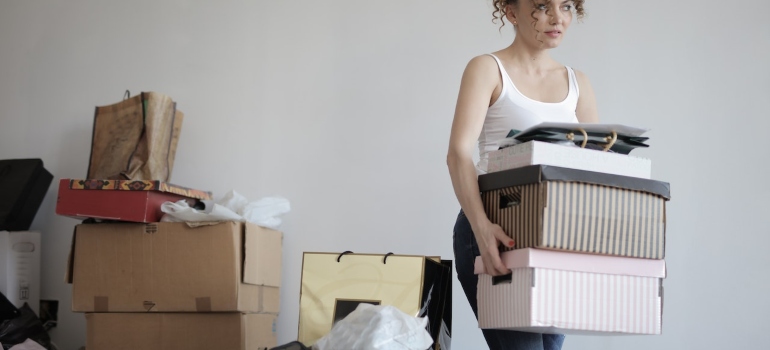 a woman carrying boxes while decluttering her condo before the move