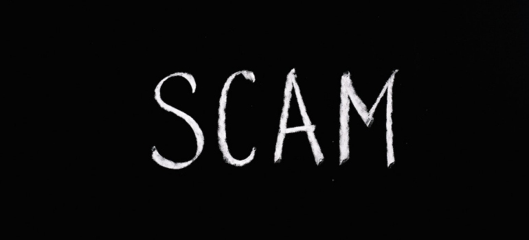 the word scam written on a black surface representing most common problems of last-minute relocation