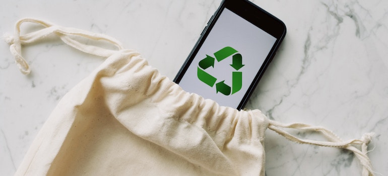 Eco-friendly bag and a phone with the recycle logo.