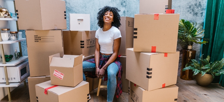 A woman sitting among cardboard boxes representing moving during peak season