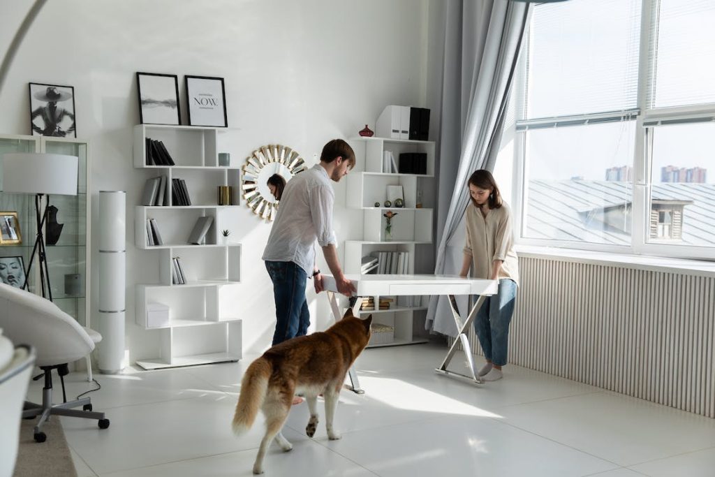 A man and a woman carrying a white table in a new office