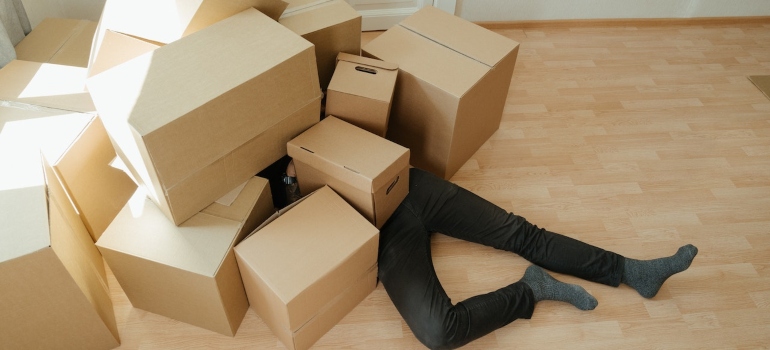 A man under cardboard boxes trying to prevent injuries when moving from NYC to Chicago