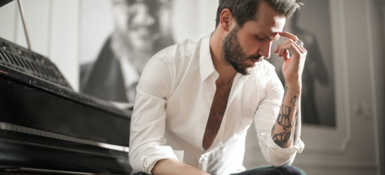 a man next to a piano thinking about moving and  packing a piano