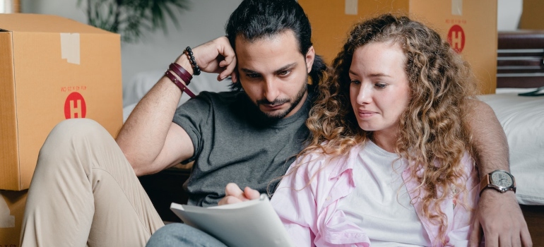 a couple surrounded by boxes making a moving plan