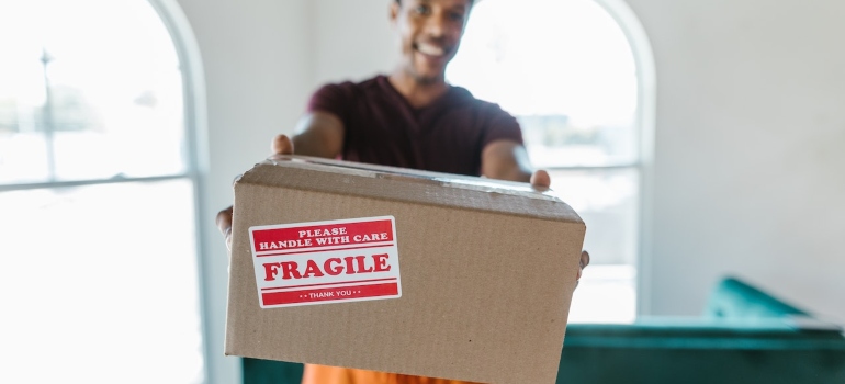 a mover holding a box labeled 