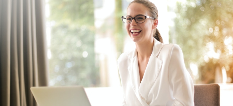 a happy woman with a laptop before moving an IT office to Brooklyn