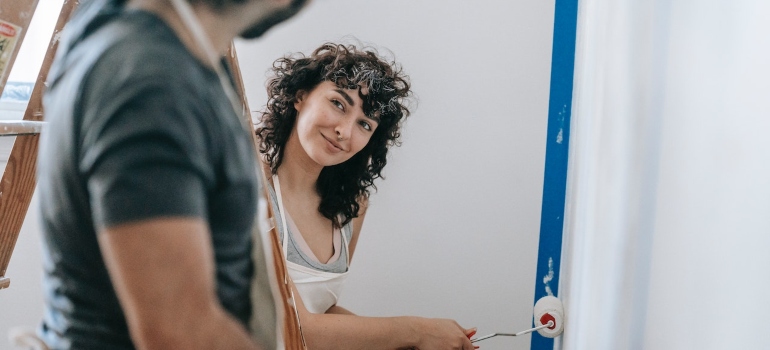 a couple painting the wall and talking about how to organize eco-friendly home renovation