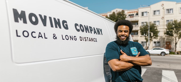 man standing next to a company van ready to help you move after comparing Downtown Brooklyn vs Brooklyn Heights