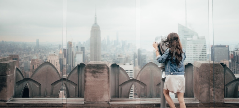 a woman standing on the top of a building enjoying NYC