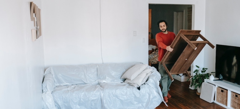 a man carrying a table before moving furniture to Vobble Hill