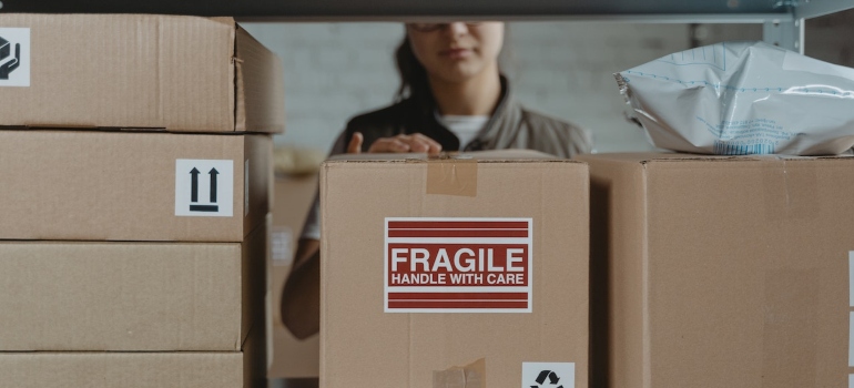 a woman labeling a box with 'fragile' after packing breakables for relocation