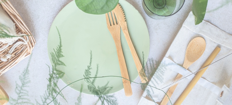 green fork, spoon, and knife on an eco-friendly plate and napkin - a good start for a green home set-up for your move to Borough Park 